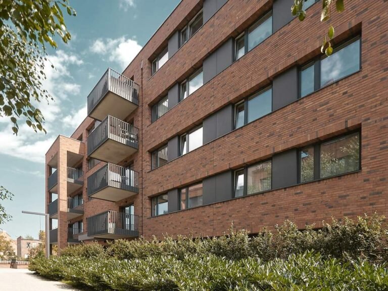 Modern red-brick apartment block with balconies and landscaped gardens